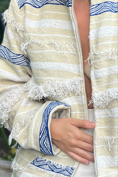 Detailaufnahme von Reißverschluss, Fransen und blauer Ethno-Borte der Jacke Aglaie