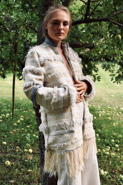 Model trägt Boho Mantel Aglaie vor Apfelbaum, Frontalansicht mit Fransensaum

Meta: Herbstliches Lifestyle-Shooting der Jacke Aglaie unter einem Apfelbaum.